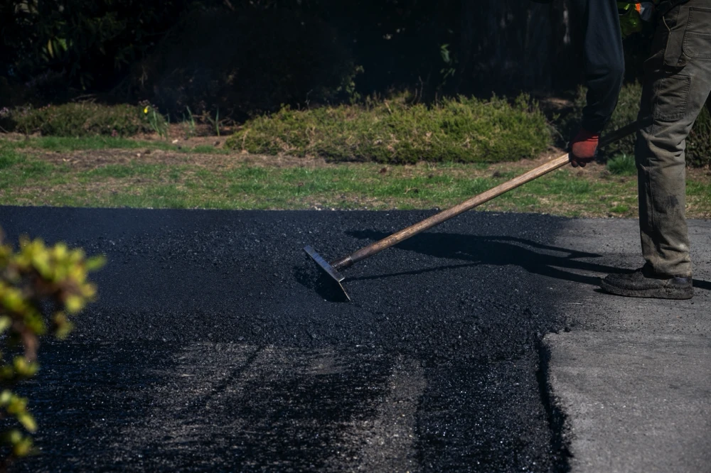 Asphalt pavement expert placing new asphalt for a broken asphalt driveway