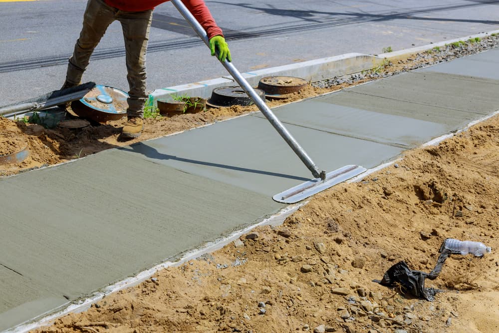 A man laying a concrete sidewalk