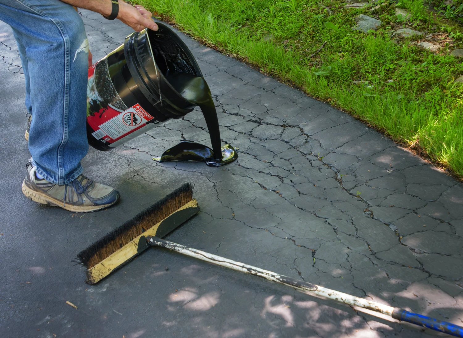 Professional Repair Service Pouring Sealant Over A Cracked Driveway